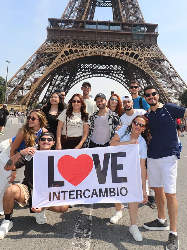 Grupo da Love Intercâmbio com bandeira em frente à Torre Eiffel